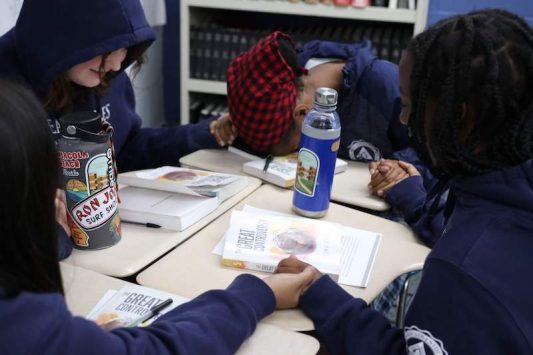 Students hold hands in prayer prior to their study of the Great Controversy. 